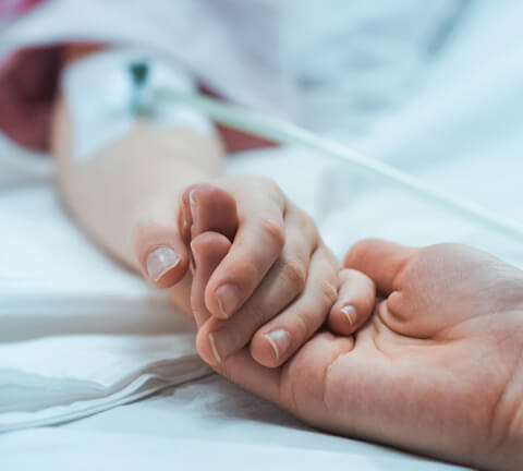 Holding loved ones hand in hospital bed with IV